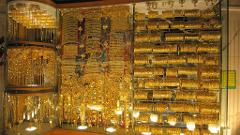 This image shows a display case filled with a large quantity of gold jewelry, primarily bangles, necklaces, and pendants, creating a dazzling, opulent scene.