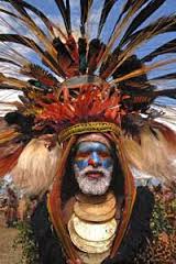 Here's a description of the image:A man in traditional Papua New Guinean attire with face paint, a large feather headdress, and layered necklaces is likely participating in the Mt. Hagen Cultural Show.