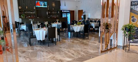 Forfait de voyage à Bangui avec visa à l'arrivée pour la République centrafricaine A well-lit restaurant with marble floors, elegant tables set for dining, and a bar stocked with bottles.