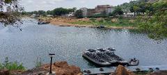 Forfait de voyage à Bangui avec visa à l'arrivée pour la République centrafricaine A fleet of rigid inflatable boats are docked on a wooden pier on a wide, calm river with a sandy bank and buildings in the background.