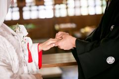 A traditional Japanese wedding scene shows the groom placing a ring on the bride's finger, both dressed in traditional wedding attire.