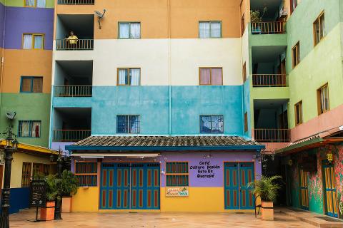 A colorful building with a cafe on the first floor and apartments above, all painted in a vibrant mix of colors.