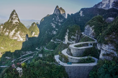 A winding mountain road snakes through lush, rocky terrain.