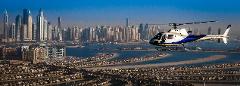 An aerial view shows a blue and white helicopter flying over Palm Jumeirah with Dubai's skyline in the background.