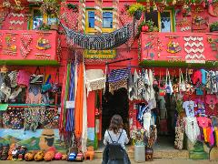 Excursión de un día al Patrimonio Cultural Zenú A colorful shop in Guatapé, Colombia, is filled with handmade goods, attracting a tourist with a backpack.