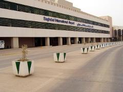 A street view of Baghdad International Airport building with planters lining the road.