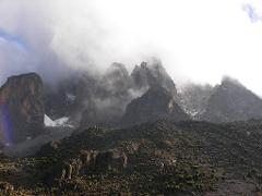 A misty mountain range with sparse vegetation under a bright sky.