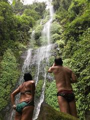 Gran Tour incluyendo Bogotá, Medellín, Nuquí y Valle del Cocora - 11 Días A couple in swimwear admire a beautiful, multi-tiered waterfall cascading down a lush, green hillside.