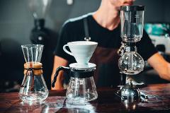 Coffeeholic Tour in Medellin A barista prepares coffee with a Chemex, V60 dripper, and siphon on a wooden counter.
