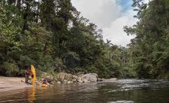 San Agustín Kayak - 9 Days Two kayakers are preparing for a river adventure in a lush, green landscape.