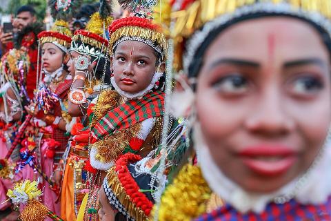 A group of children in vibrant, traditional costumes and makeup participate in a cultural event or festival in Bangladesh.