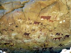 This image shows ancient rock art featuring depictions of animals and human figures painted on a cave wall.