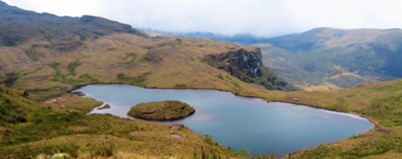 A picturesque lake with a small island nestled amidst rolling hills and mountains.
