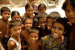 A group of smiling children in Bangladesh huddle together, looking at the camera with joyful expressions.