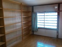 An empty room with wooden shelves and a window with blinds is shown.