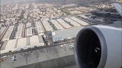 Aerial view from an airplane window showing the engine and cityscape with buildings including DNATA Air Cargo.