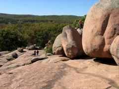 O vedere pitorească a Parcului de stat Elephant Rocks, cu bolovanii săi masivi de granit și câțiva oameni care explorează peisajul.