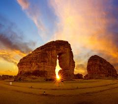 A majestic rock arch frames the setting sun, painting the sky with vibrant colors.