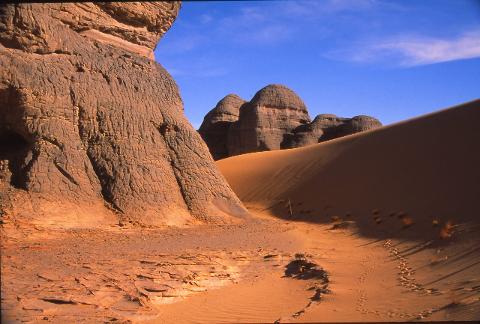 The Quest of the Tibesti Mountains A vast desert landscape with towering sandstone formations under a bright blue sky.