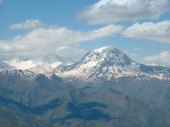 A scenic view of snow-capped mountains under a blue sky with scattered clouds.