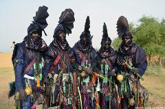 Five elaborately dressed men in traditional attire stand outdoors in Niger.
