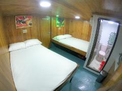 A small cabin with two beds and an en-suite bathroom with pink toilet.