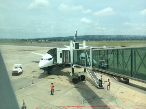 A passenger airplane is parked on the tarmac and connected to a boarding bridge at an airport.