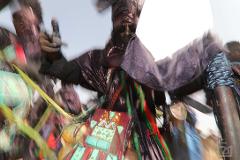 A man in traditional African clothing, including a mask, is captured in a dynamic, blurred motion.