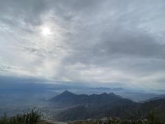 A misty landscape shows multiple layers of mountains under an overcast sky.