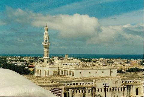 Tur privat de 3 zile în Mogadiscio (istorie, cultură și coastă) A high-angle shot showcases the Mosque of Islamic Solidarity in Mogadishu, Somalia, with its tall minaret towering over the surrounding cityscape and the sea in the background.