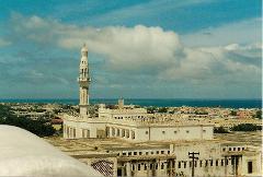 Tur privat de 3 zile în Mogadiscio (istorie, cultură și coastă) A high-angle shot showcases the Mosque of Islamic Solidarity in Mogadishu, Somalia, with its tall minaret towering over the surrounding cityscape and the sea in the background.