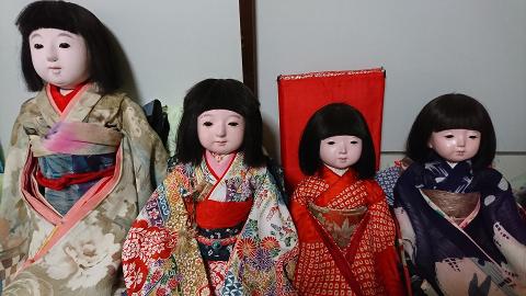 Four Ichimatsu dolls in traditional kimonos are arranged in a row, showcasing the intricate craftsmanship of Japanese doll making.