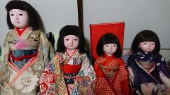 Four Ichimatsu dolls in traditional kimonos are arranged in a row, showcasing the intricate craftsmanship of Japanese doll making.