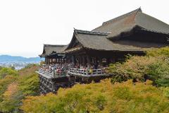 A beautiful image of Kiyomizu-dera Temple in Kyoto, Japan, with its iconic wooden stage bustling with visitors and surrounded by vibrant autumn foliage.