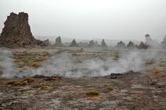 A desolate landscape with towering rock formations and geothermal activity.