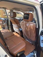 A peek inside a car shows tan leather seats, headrest monitors, and diamond-stitched floor mats, with the front seats covered in protective plastic.