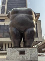 Gran Tour incluyendo Bogotá, Medellín, Nuquí y Valle del Cocora - 11 Días A bronze sculpture of a headless, nude female torso stands on a marble base in front of a modern building.