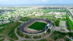 Tur privat de 3 zile în Mogadiscio (istorie, cultură și coastă) An aerial view shows a packed stadium in Mogadishu surrounded by a city with a coastline in the background.