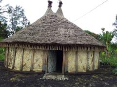 The image shows a traditional thatched-roof building with woven bamboo walls, a unique structure found along the Sepik River.