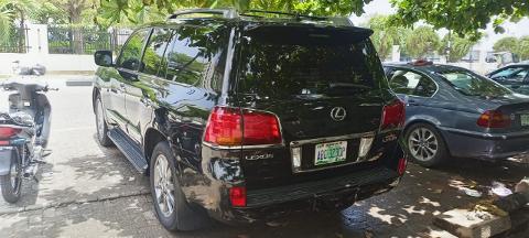 A black Lexus LX570 SUV is parked next to a motorcycle and a blue sedan, displaying its license plate "ABC-323DP".