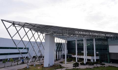 The Islamabad International Airport is a modern building with a geometric design, featuring a white diamond-patterned canopy and glass facade.