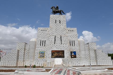 Tur privat de 3 zile în Mogadiscio (istorie, cultură și coastă) A large, white brick monument topped with a statue of a person on horseback stands under a partly cloudy blue sky.