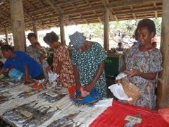 A group of women are at a fish market with a variety of goods on display in Rabaul, Papua New Guinea.
