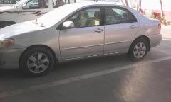A silver Toyota Corolla parked in a parking lot, with a white SUV parked next to it.