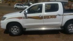 Un pick-up Toyota Hilux bianco con la scritta 4x4 parcheggiato su una strada.