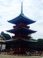 Billedet viser en tre-etagers pagode, en traditionel japansk arkitektonisk struktur med flere lag tage, under en overskyet himmel.
