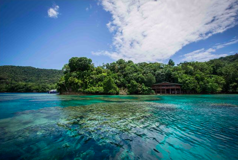 A scenic view of turquoise water, lush green islands, and a clear blue sky with scattered clouds.