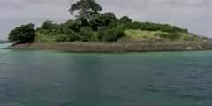 This image shows an island covered in lush green vegetation in the San Blas Islands in Guna Yala, with turquoise waters surrounding it.
