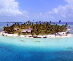 An aerial view of a tropical island paradise with palm trees, white sand beaches, thatched-roof huts, and clear turquoise waters.