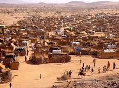 Certainly! Here's a description of the image:The image shows a densely packed, makeshift refugee camp or settlement in a barren, arid landscape, with numerous small dwellings constructed from basic materials.
